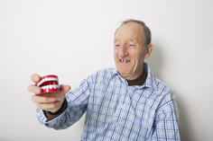 Happy man holding dentures