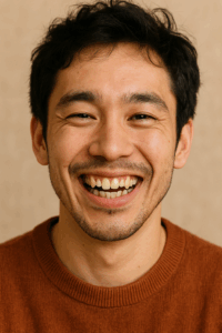 A close-up photo showing a male individual smiling with distinct yaeba teeth, showcasing crooked canine teeth and an overall charming appearance