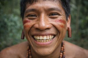Photorealistic portrait of an Indigenous Amazonian adult smiling, showing shortened teeth with flattened incisal edges and visible dentin consistent with tooth wear from diet.